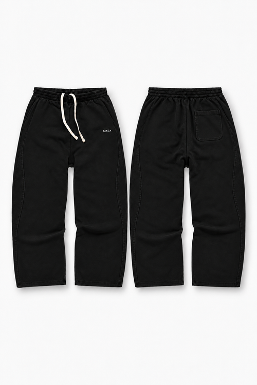 YAKCA CORE black oversized sweatpants with curved panel seams and ivory drawstrings, front and back views